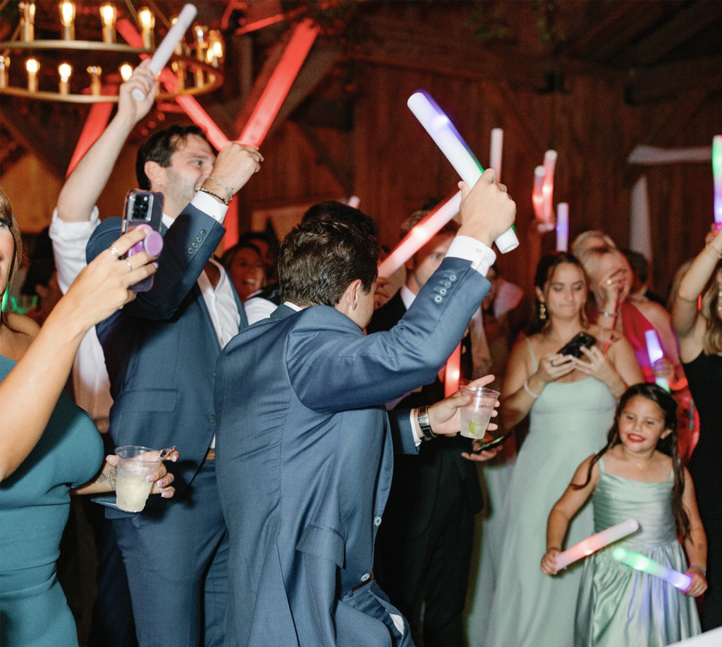 Guests dancing with LED glow sticks on a packed ML Event Entertainment wedding dance floor.