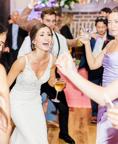 Bride laughing and dancing with a drink on the wedding reception dance floor with ML Event Entertainment.
