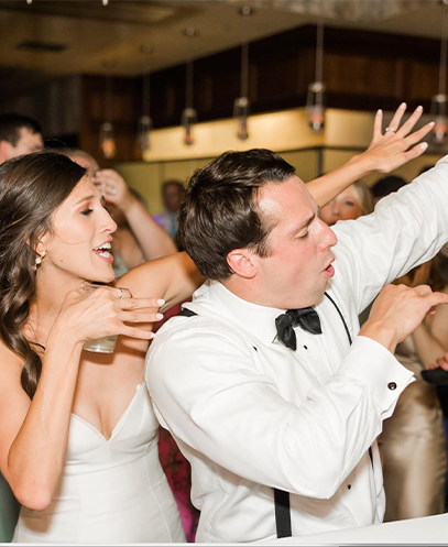 Bride and groom dancing with hands in the air during their wedding reception with ML Event Entertainment.